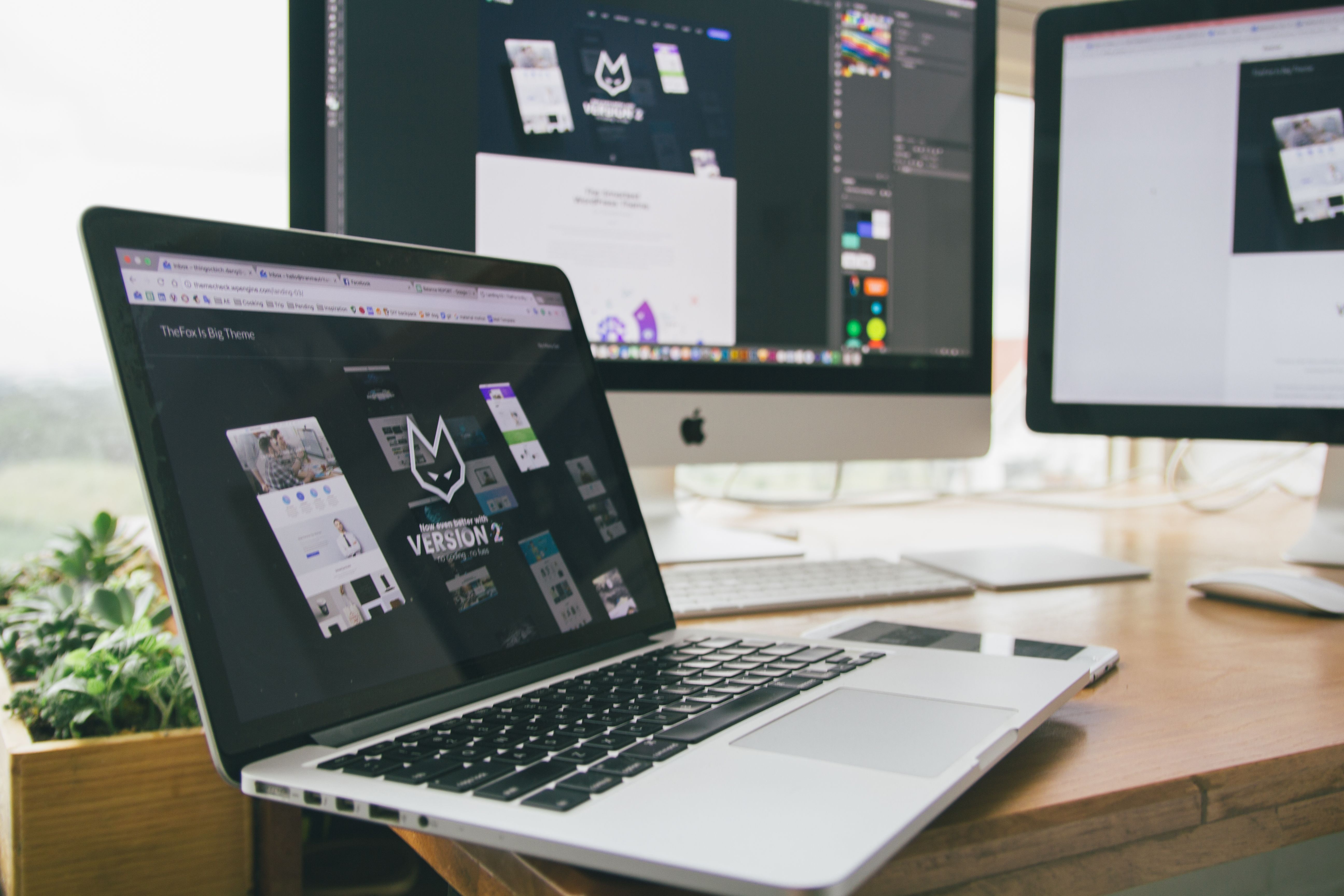 Web design workspace with multiple monitors showing site builds in progress